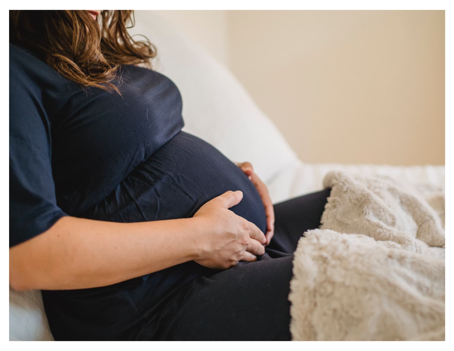 A pregnant woman holding her baby bump.